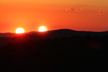 Surreal landscape image at sunset with two suns.