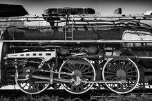Huge Vintage Steam Locomotive, Red Painted Steel Wheel Detail Close Up. Coal-powered Steam Train Stands On A Siding. Classic Gigantic Heavy Railway Machinery. Side View Of Power Parts Of Machine.