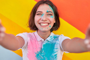 Wall Mural - Cheerful female hipster taking selfie during paint party
