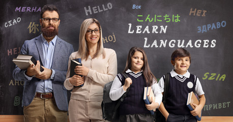 Wall Mural - Language teachers and pupils posing in front of a blackboard with text learn languages