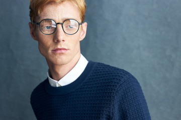 portrait of a young handsome red-haired man with freckles on a dark background he is wearing a class