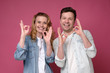© Viktor Koldunov - Good looking smiling man and woman showing OK sign with two hands. Positive facial human emotion. Studio shot
