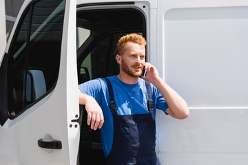 Wall Mural - Young loader talking on cellphone while standing near truck outdoors