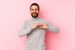 © Asier - Young long hair man isolated on a pink background smiling and showing a heart shape with hands.
