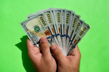 USA national currency. US dollar money banknotes. Young man holds in his hands American dollars on green background. USD.