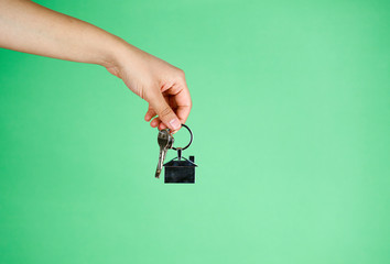 House key in woman hand. green background