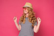 © Viktor Koldunov - Beautiful mature woman wear sunglasses and hat smiling. Enjoy summer holiday isolated on pink background.