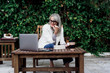 © Eloisa Ramos/Westend61 - Smiling female entrepreneur looking at laptop while enjoying lunch against plants