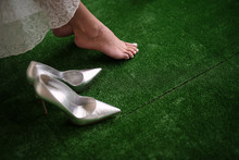 Female Beautiful Foot On Green Carpet, Silver Shoes Are Next To