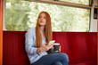 © PETE  MULLER/Westend61 - Thoughtful woman holding disposable glass and smart phone while sitting in train