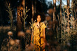Young woman with afro hair standing amidst plants in forest during sunset
