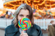 © William Perugini/Westend61 - Close-up of young woman holding colorful lollipop at amusement park