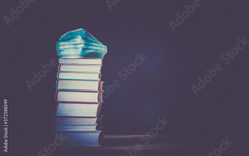 Fotomural back to school during covid pandemic pile of books and medical mask