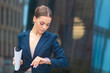 © Евгений Шемякин - Beautiful businesswoman in formal suit, jacket, attractive woman in hurry, young girl , pretty lady with documents in hand looking at her wrist watch, checking time on watches, rushing, have no time