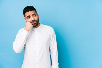 Wall Mural - Young latin man against a blue  background isolated who feels sad and pensive, looking at copy space.