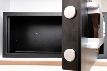 Inside of an empty unlocked metal safety box with door opened ajar on a hotel cabinet shelf for users to store their personal belongings and important valuables.