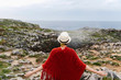 © Alberto Menendez/ADDICTIVE STOCK - Back view of unrecognizable female tourist in red knitted poncho and hat standing on rocky coast near geyser and admiring nature while visiting Jesters of Arenillas in Llanes in Spain