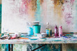 © Alvaro Montero/ADDICTIVE STOCK - Plastic bottles with colorful paints and empty containers near artist tools on dirty table near multicolored wall with uneven surface in art studio