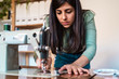 © Alvaro Sanchez/ADDICTIVE STOCK - Crop serious ethnic craftswoman extending thin thread while using modern metal sewing machine with spool on top on wooden table in workshop