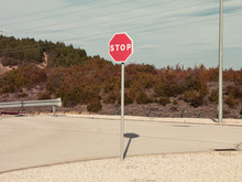 Round Red Prohibitory Road Sign With Word Stop On Empty Asphalt Roadway In Dry Rural Terrain