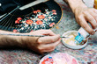 © Javier Ballester/ADDICTIVE STOCK - From above crop anonymous male artist pouring white gouache into palette while drawing floral pattern on hand fan in workshop