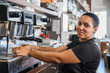 © Javier De La Torre/ADDICTIVE STOCK - Side view of positive ethnic barista pouring hot coffee into cup from coffee machine while working in bar
