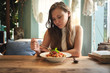 © Luis Gomez/ADDICTIVE STOCK - Upset young female relaxing at wooden table with served plate of delicious pasta in cozy restaurant on sunny day