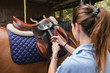 © Raquel Arocena/ADDICTIVE STOCK - Back view of serious female equestrian putting saddle on chestnut horse before dressage