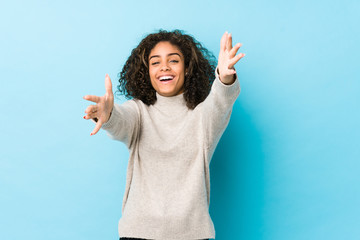 Wall Mural - Young african american curly hair woman feels confident giving a hug to the camera.