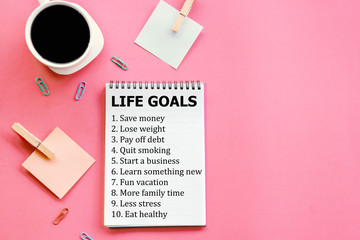 life goals setting, wish list on notebook flat lay on pink background with coffee cup