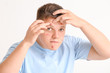 © Pixel-Shot - Teenage boy with acne squishing pimples on light background