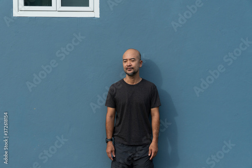Fotomural portrait of Asia bald beard 40s man in casual cloth on blue wall background