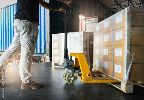 Shipment, Delivery, Cargo export Worker unloading heavy pallet goods, his using hand pallet jack loading into container truck. Road freight cargo transportation and Logistics.