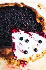 Wall Mural - A close-up of a black currant galette on baking paper on white background