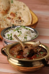 Mutton curry Served with naan or bread and jeera rice over wooden background.