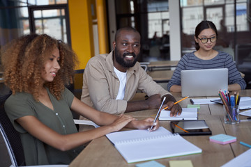 Sharing fresh ideas. Young multicultural business team working together in the modern coworking space, discussing new project while having a meeting