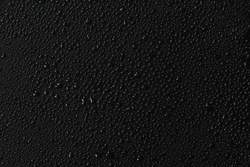 Water droplets on black background. Close-up photo of small water drops on black background.