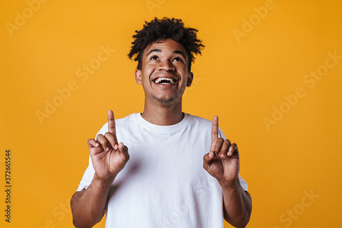 Fotomural Image of happy african american guy smiling and pointing fingers upward
