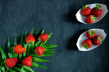 Strawberries in white boats on dark board