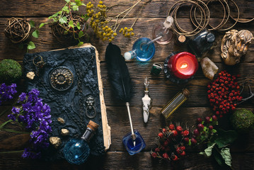 spell book, magic potions and other various witchcraft accessories on the wizard table background.