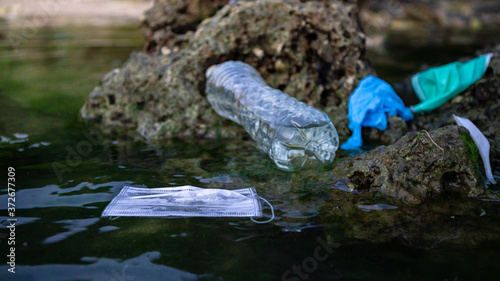 Coronavirus polluting environment. Medical mask waste and plastic bottle