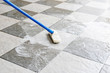 Cleaning the tile floor with a long-handled floor brush.