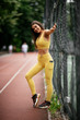 Beautiful woman training on running track. Young woman in yellow sportswear..