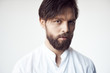 © monchak - portrait photo of a handsome bearded man with brown hair and eyes on white background, he is dressed in a white linen shirt and looks at the camera