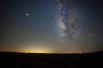 Wall Mural - Milky Way stars above a vast prairie with a distant fire 
