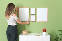 Woman Hanging Blank Photo Frames On Wall