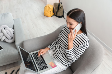 Wall Mural - Woman with laptop booking tickets online at home