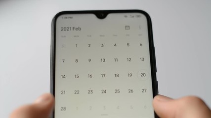 Close-up of a man's hand using a smartphone calendar application on a white background