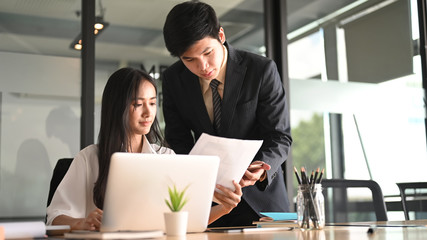 Wall Mural - A businessman is teaching his secretary about their job at the wooden working desk.