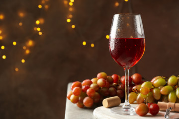 Wall Mural - Composition with glass of wine and grape on brown background with blurred lights